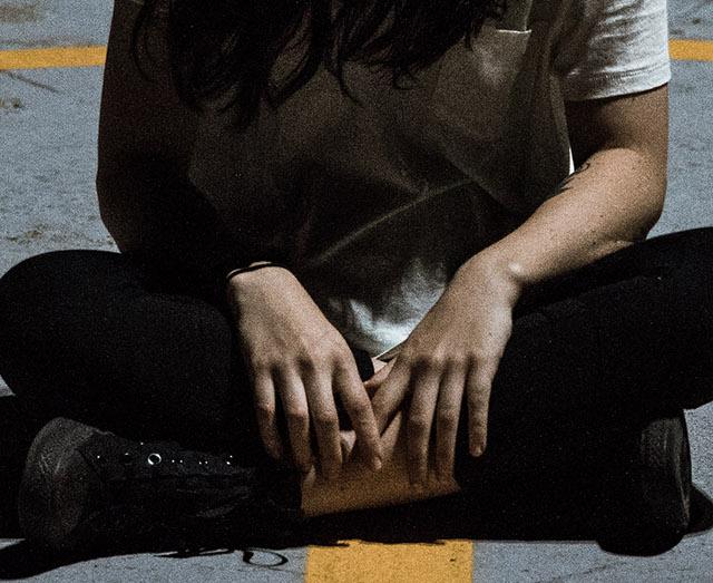 photo of a person sat on the ground slumped over with hands in lap